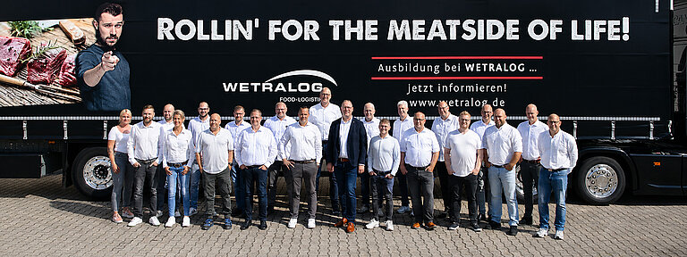 Wetralog-Team vor einem schwarzen Sattelzug mit Werbung für Ausbildung und Karriere.