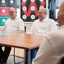 Zwei Wetralog-Mitarbeiter lachen während einer Besprechung am Konferenztisch.