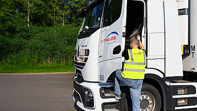 Wetralog-Fahrschüler in Warnweste steigt in die Fahrerkabine eines weißen Lkw ein.
