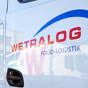 Nahaufnahme des Wetralog-Logos auf der Tür eines weißen Lkw.